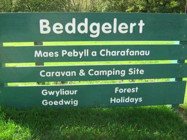 a large green sign in green stating the beddgelert caravan and camping site